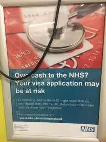 Picture of a poster put up in an NHS hospital. It shows a stethoscope and a bank card. It says 'Owe cash to the NHS? Your visa application may be at risk.'